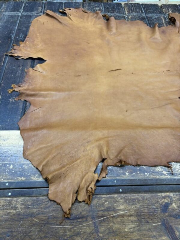 Tanned leather hide on wooden table.