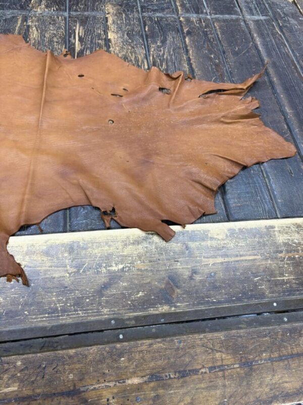 Tanned leather piece on wooden surface.