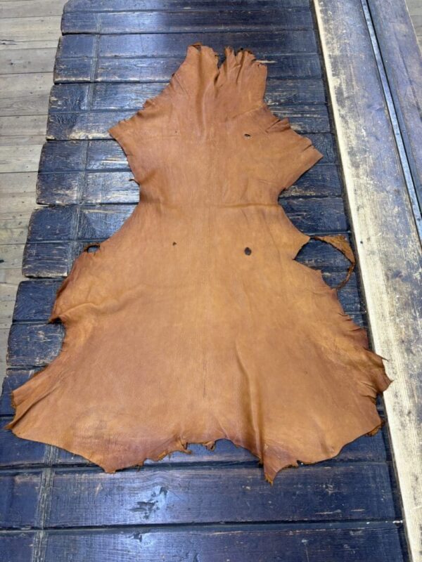 Tan leather hide on wooden surface.
