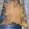 Tanned leather hide on wooden surface.