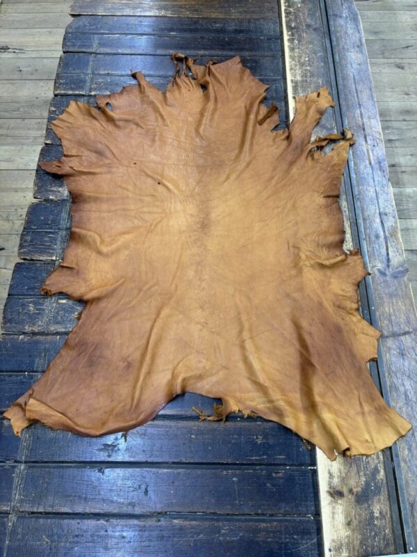 Tanned leather hide on wooden surface.