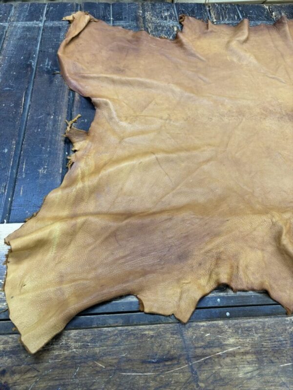 Tanned leather hide on wooden surface.