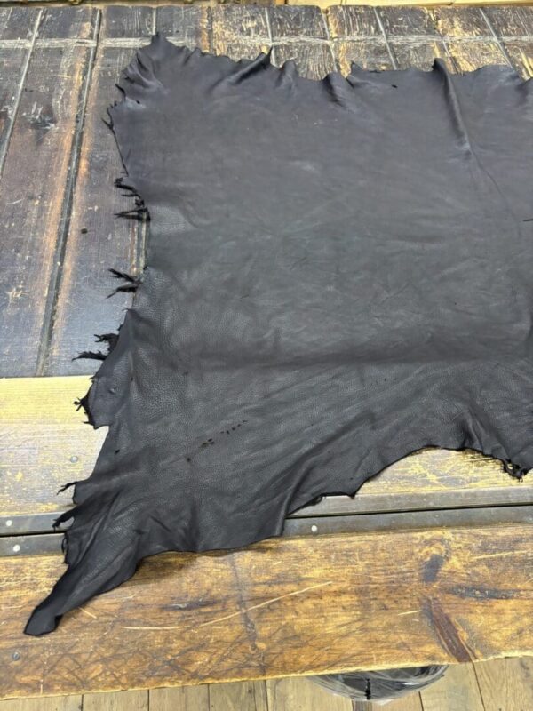 Black leather hide on wooden table.