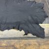 Black leather hide on wooden table.