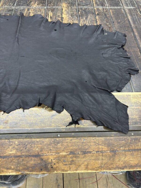 Black leather hide on wooden table.