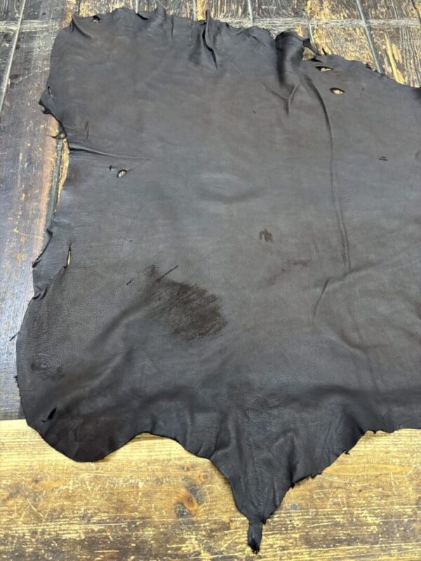 Worn black leather hide on wooden surface.