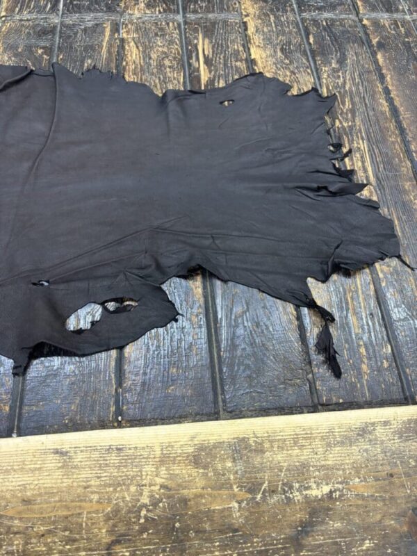 Black leather piece on wooden surface.