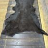 Black animal hide on wooden surface.