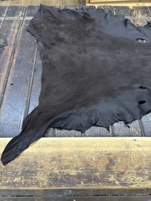 Black leather hide on wooden table.