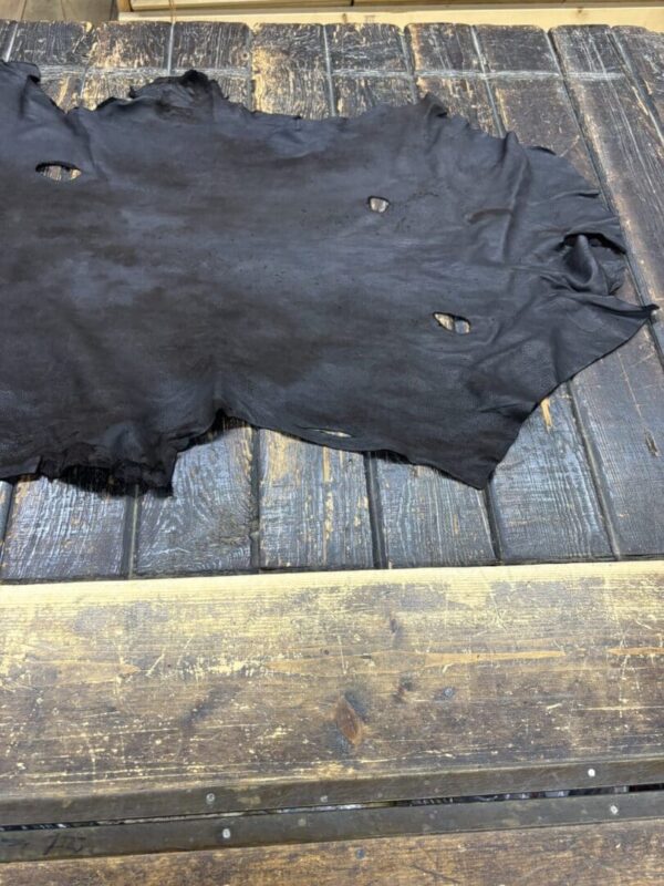 Black leather hide on wooden table surface.