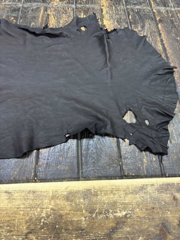 Worn black leather hide on wooden surface.