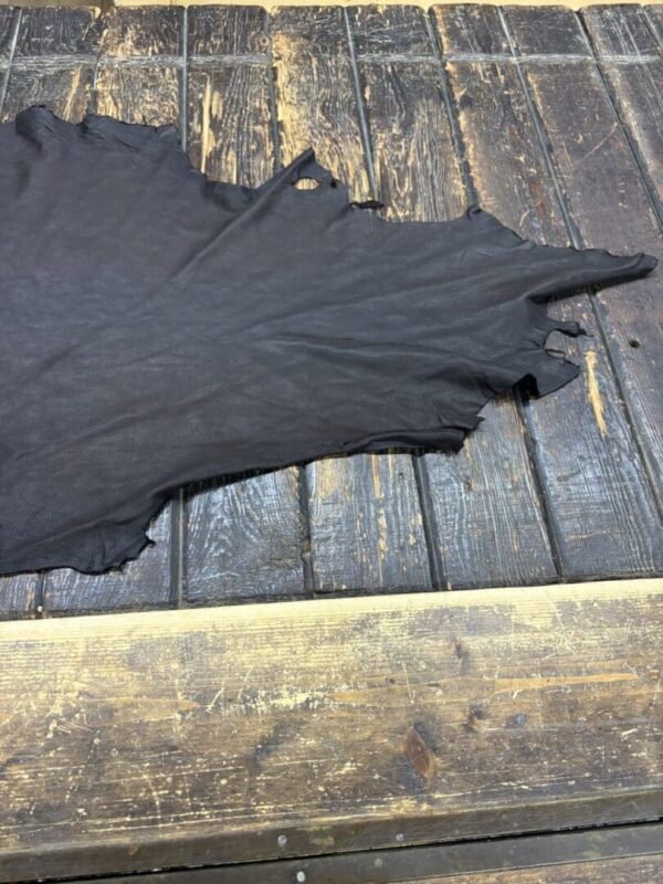 Black leather hide on wooden table.