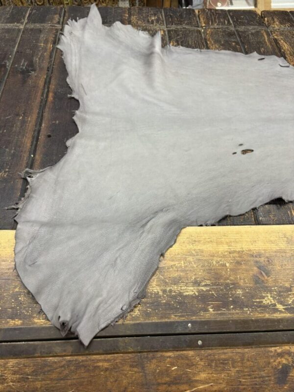 Gray leather hide on wooden table surface.