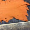 Orange leather hide on wooden table surface.