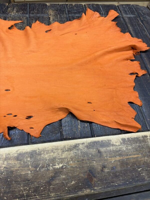 Orange leather hide on wooden table surface.