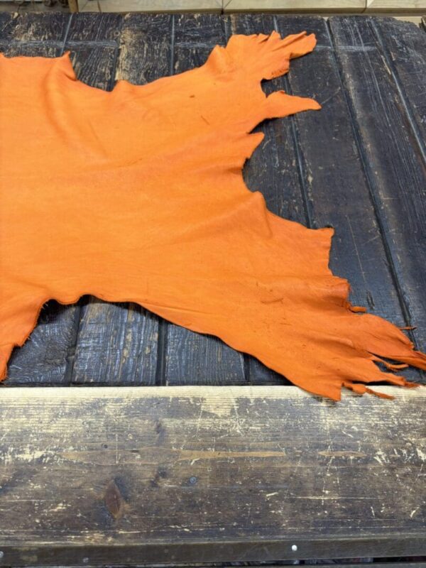 Orange leather hide on wooden table.