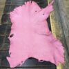 Pink leather laid out on a wooden table.