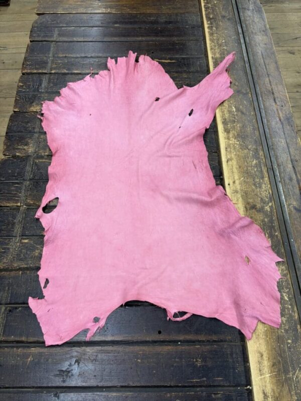 Pink leather laid out on a wooden table.