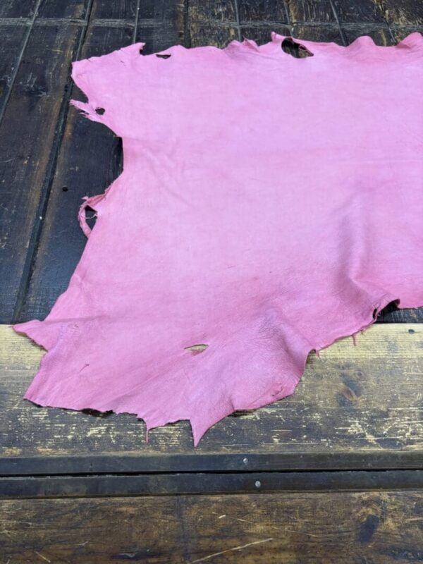Pink piece of leather on wooden surface.