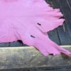 Pink leather hide on wooden table.