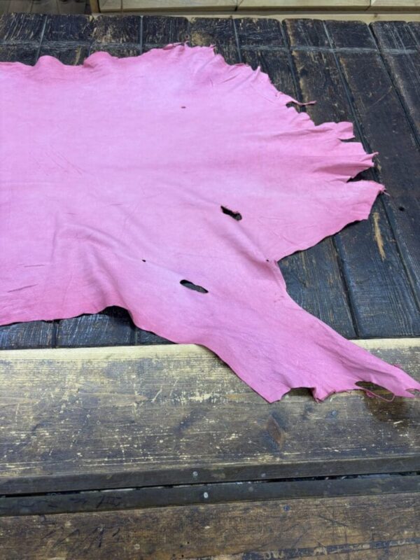Pink leather hide on wooden table.