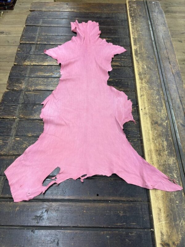 Pink leather hide on wooden table.