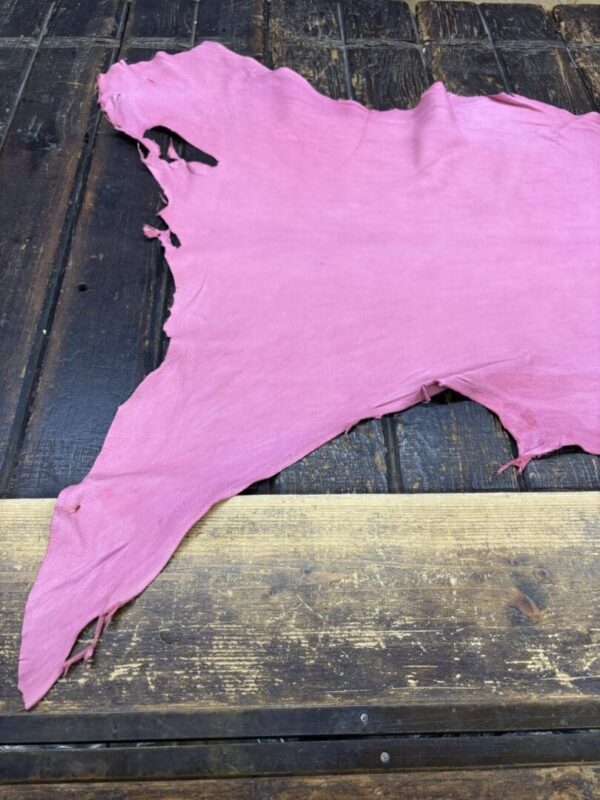 Torn pink fabric on wooden surface.