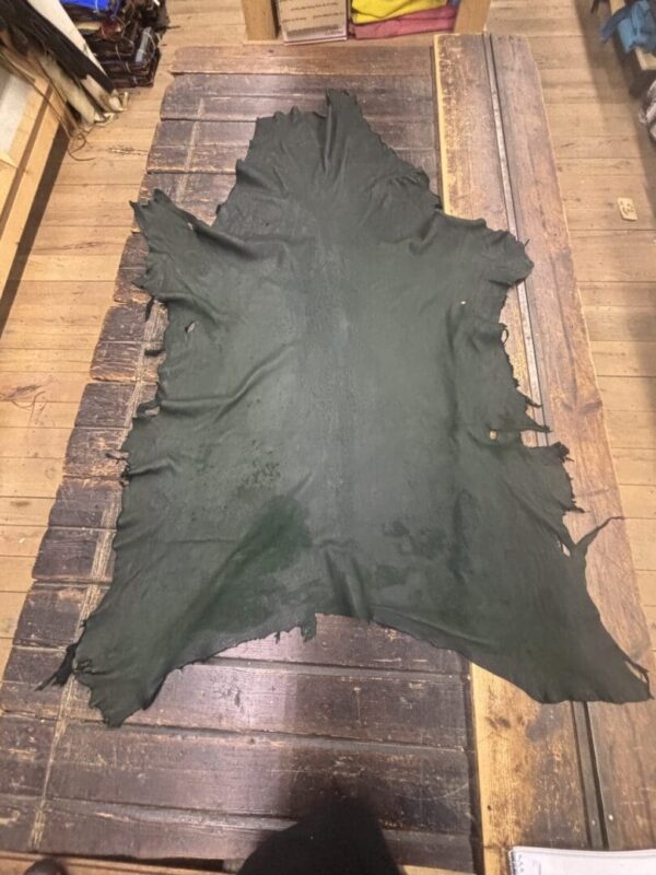 Green leather hide laid on wooden surface.
