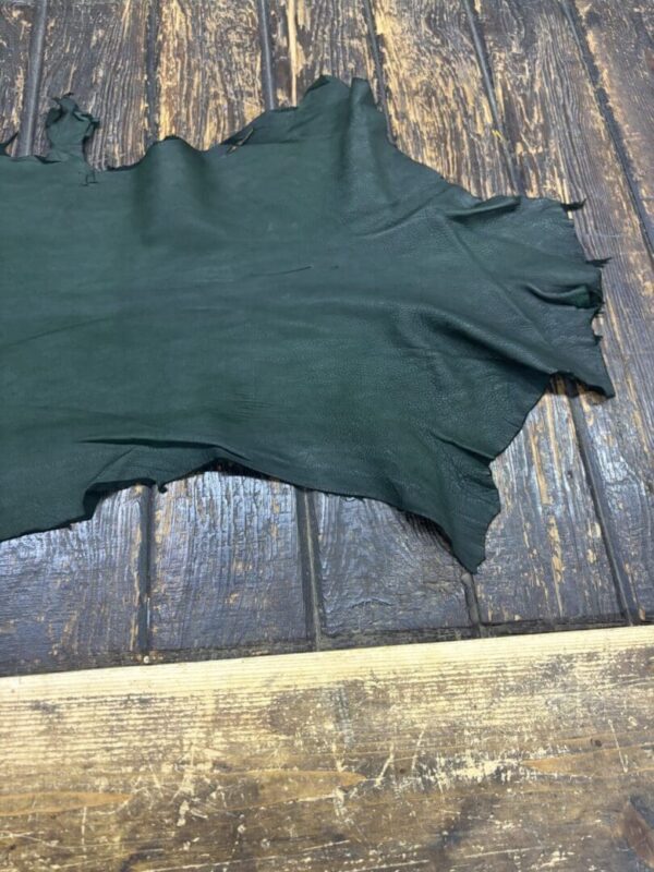 Green leather piece on wooden surface.