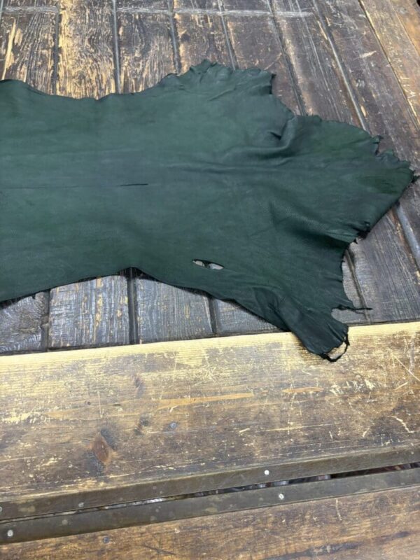 Green leather piece on wooden surface.