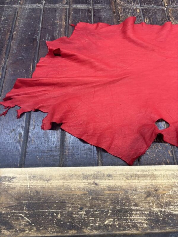 Red leather piece on wooden surface.