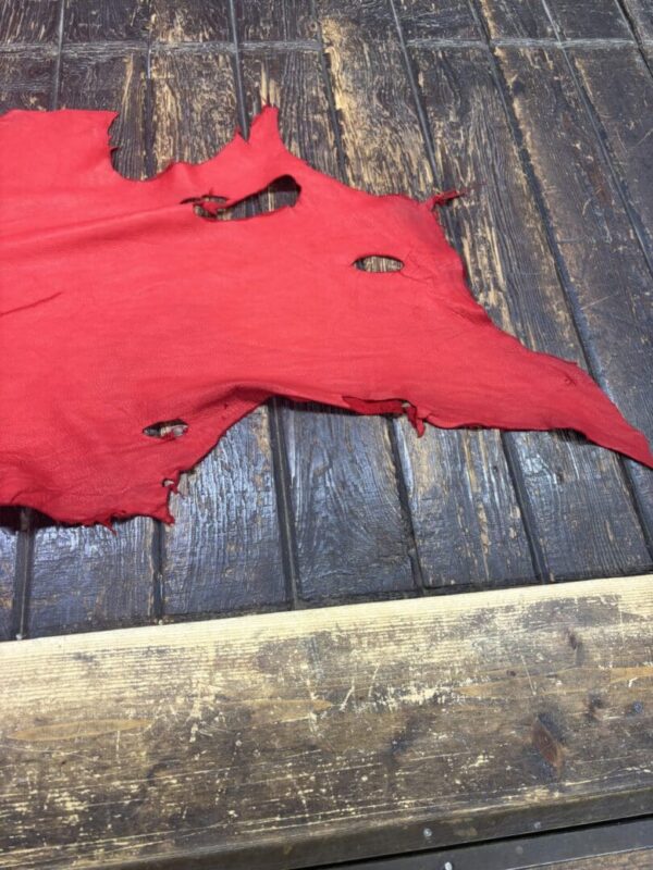 Tattered piece of red fabric on wooden floor.