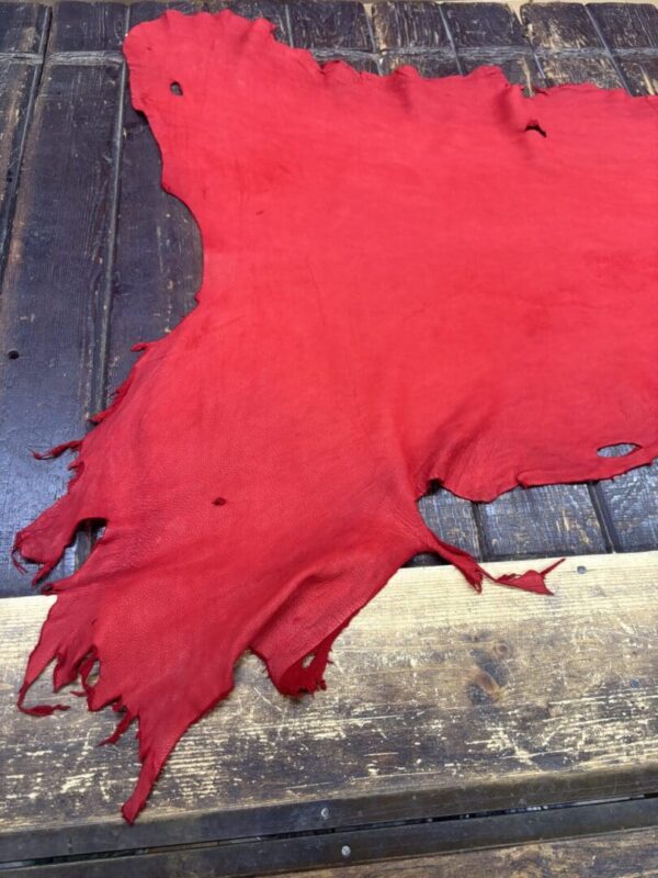 Red leather piece on wooden surface.