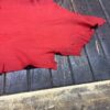 Red fabric with irregular edges on wooden surface.