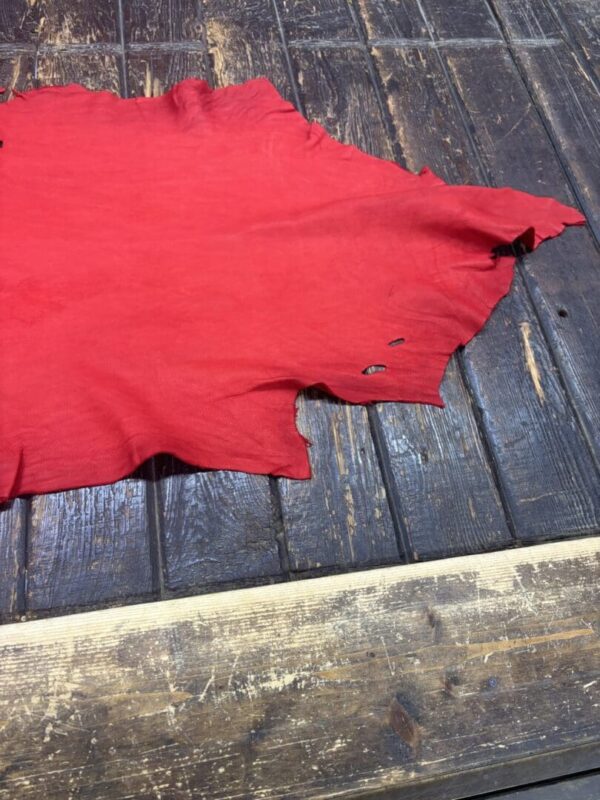 Red fabric with irregular edges on wooden surface.