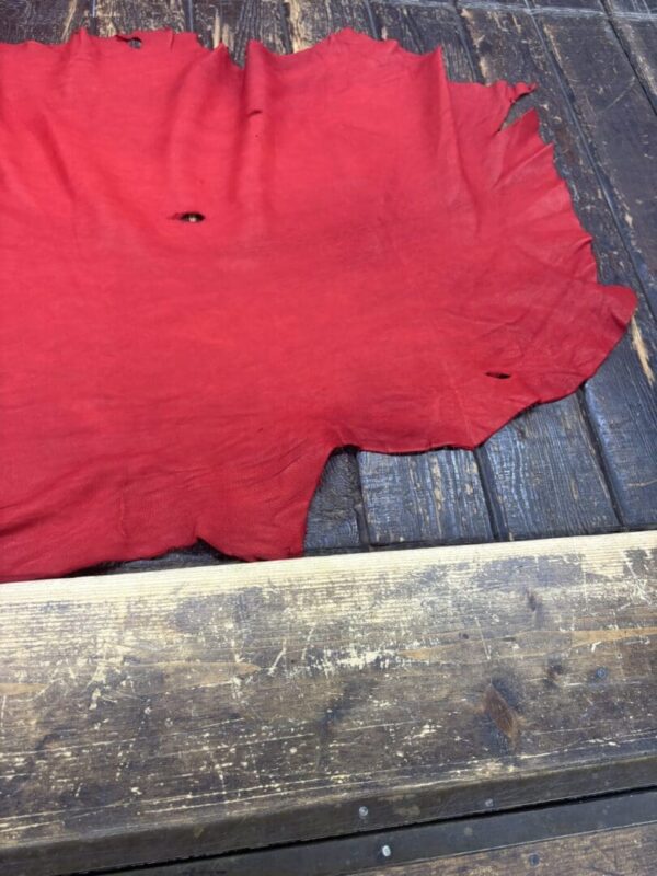 Red leather piece on wooden surface.