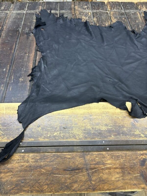 Black leather piece on wooden surface.