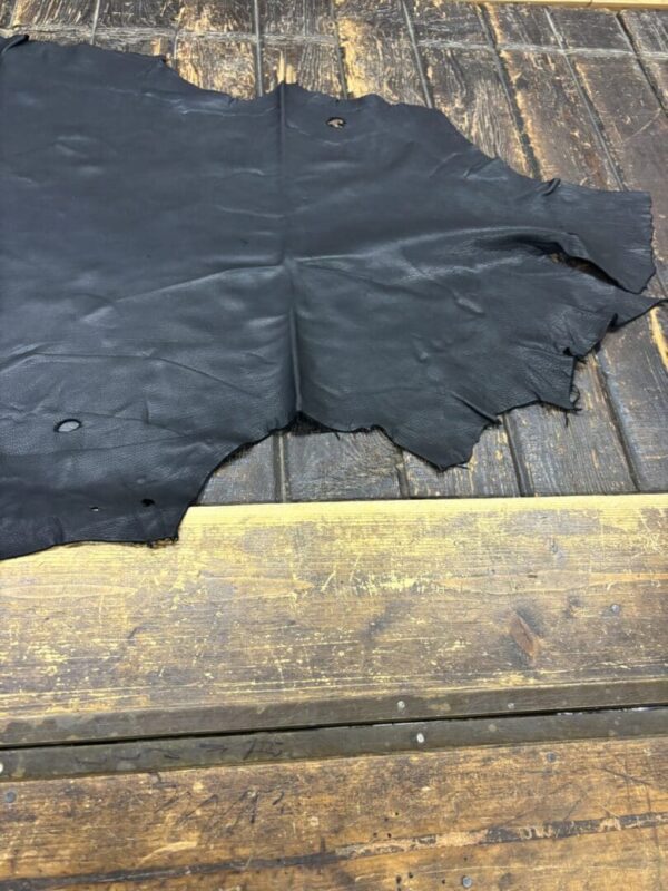 Black leather laying on wooden surface.