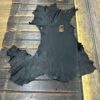 Black leather hide laid on wooden surface.