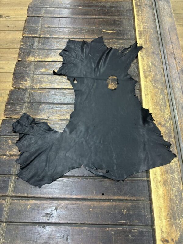 Black leather hide laid on wooden surface.