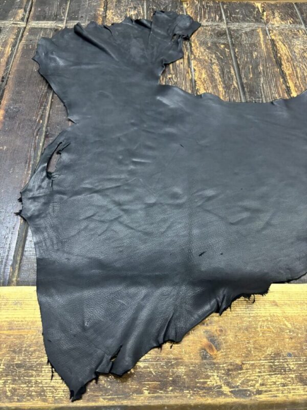 Black leather piece on wooden table.