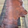 Large piece of brown leather on wooden surface.