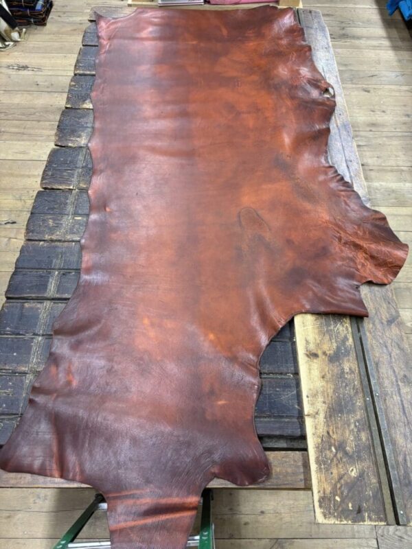 Large piece of brown leather on wooden surface.