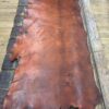 Tanned leather hide on wooden table.