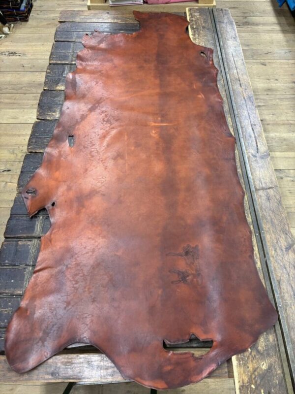 Tanned leather hide on wooden table.