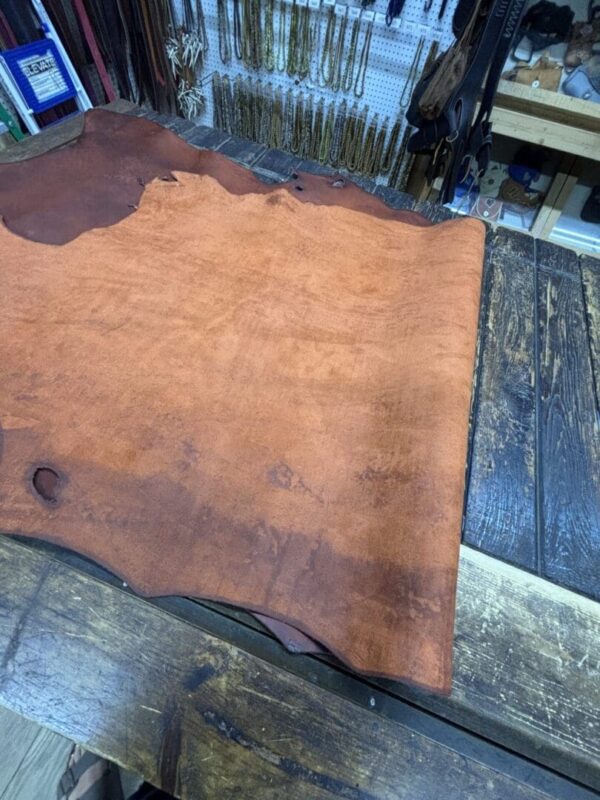 Leather hide on wooden workbench surface.