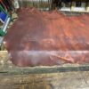 Brown leather hide on a wooden workbench.