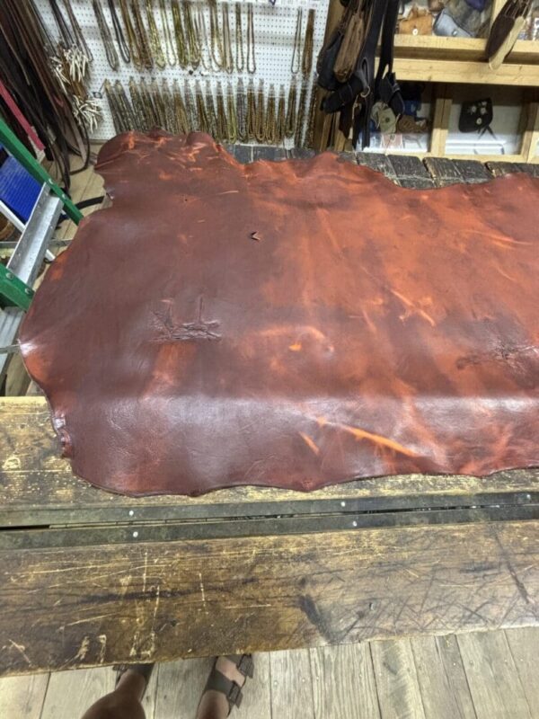 Brown leather hide on a wooden workbench.