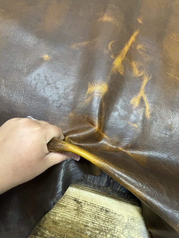 Hand holding a piece of brown leather.