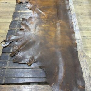IMG_2451 Brown leather hide laid on wooden surface.